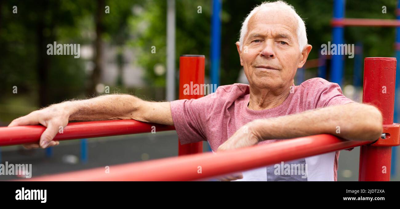 Älterer sportlicher Mann, der im Park parallel Barren macht Stockfoto