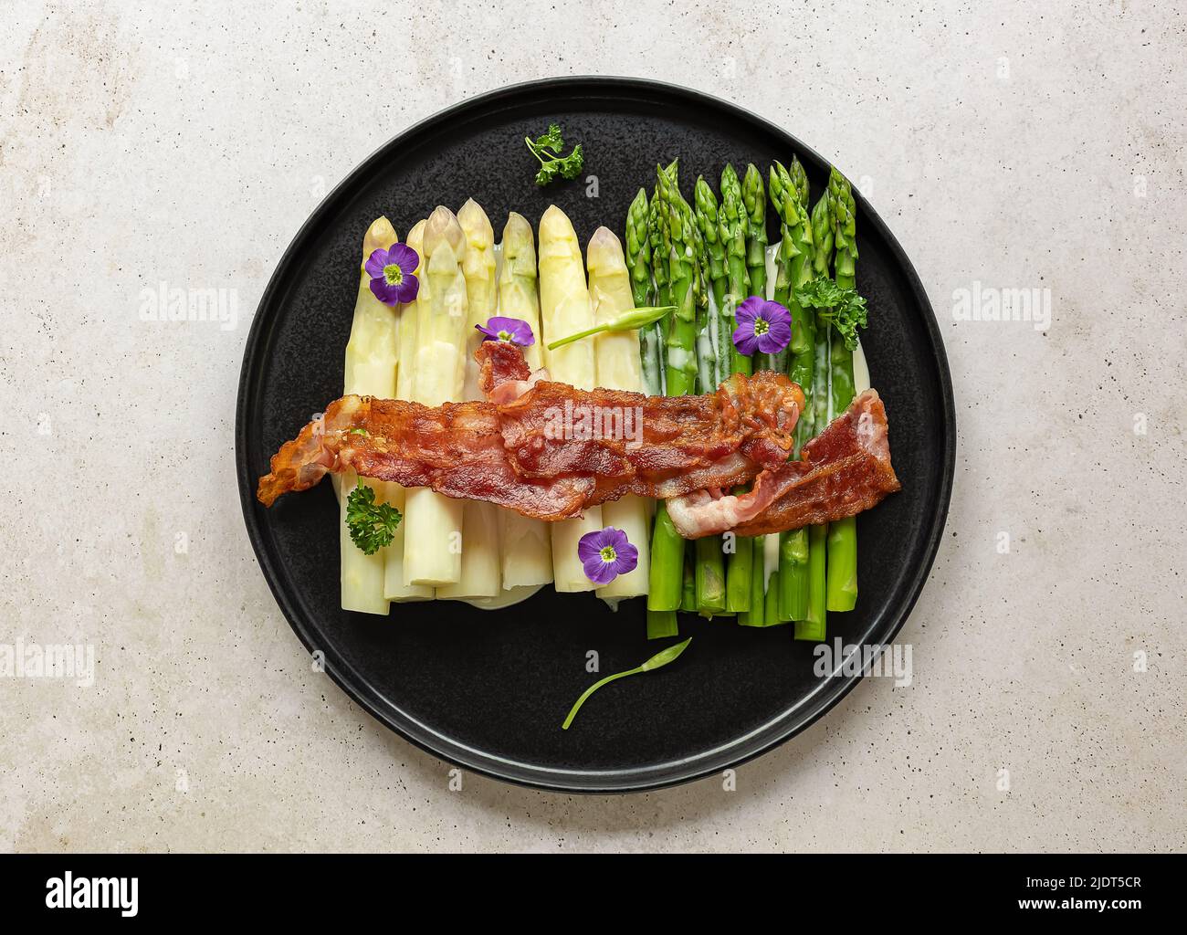 Grüner und weißer Spargel mit gebratenem Speck. Stockfoto