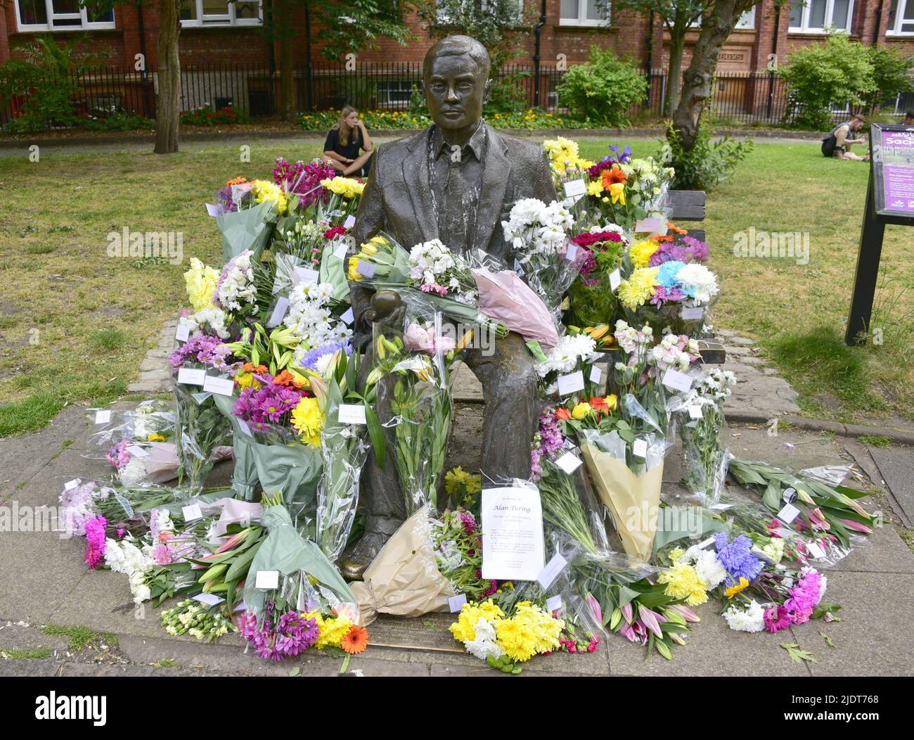 Manchester, Großbritannien. 23. Juni 2022. Blumensträuße, die am 23. Juni in Sackville Gardens im Zentrum von Manchester, Großbritannien, in der Alan Turing-Statue zum Geburtstag von Turing hinterlassen wurden. Turing gilt als der Vater der theoretischen Computerwissenschaft und künstlichen Intelligenz, spielte eine wichtige Rolle bei der Entwicklung von frühen Computern an der Universität Manchester und war ein berühmter Codebrecher aus dem Zweiten Weltkrieg. Die Wohltätigkeitsorganisation „Gleichstellungszeit“ übernimmt die Führung und hinterlässt Blumen an diesem Tag. Kredit: Terry Waller/Alamy Live News Stockfoto