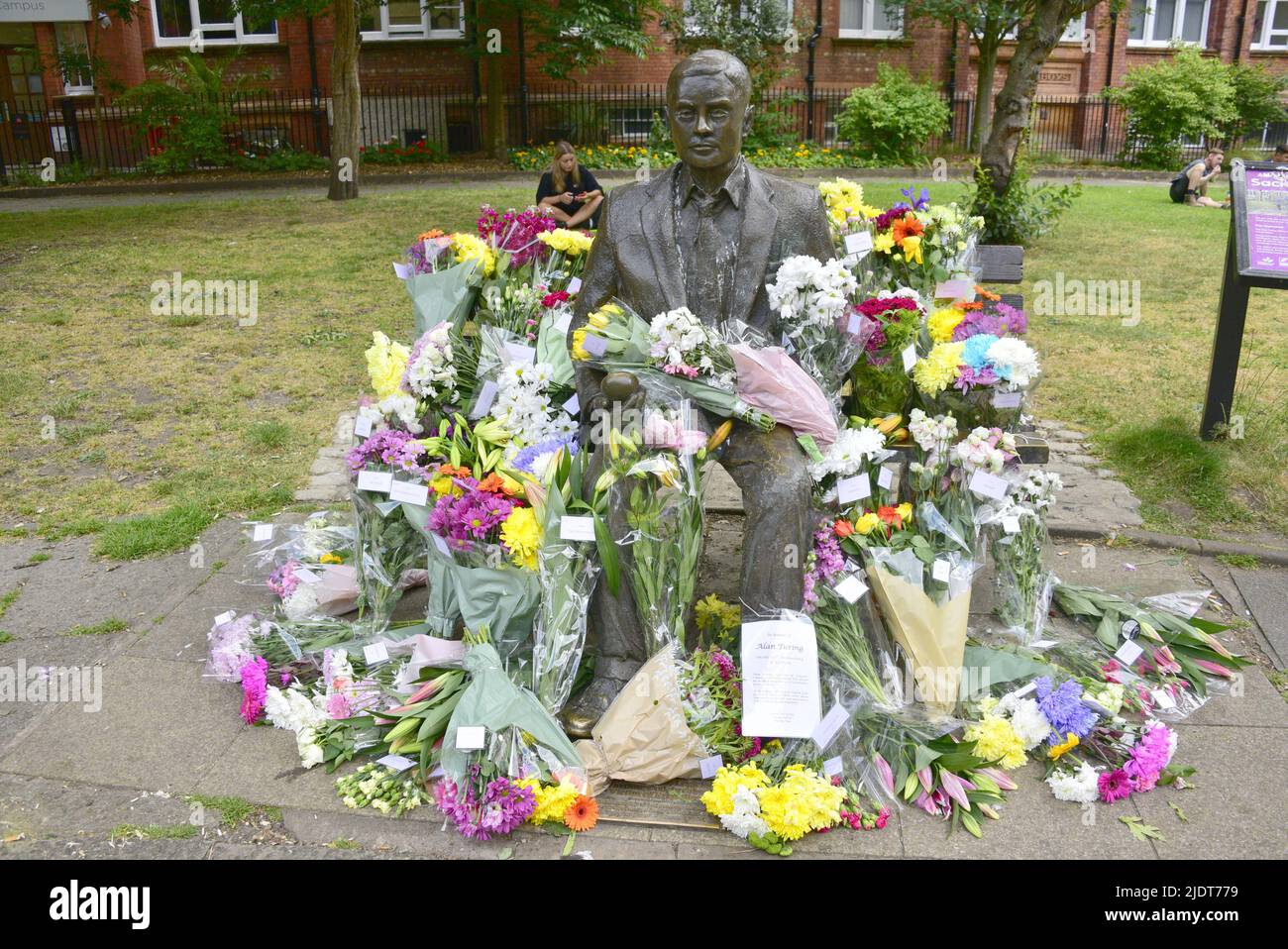 Manchester, Großbritannien. 23. Juni 2022. Blumensträuße, die am 23. Juni in Sackville Gardens im Zentrum von Manchester, Großbritannien, in der Alan Turing-Statue zum Geburtstag von Turing hinterlassen wurden. Turing gilt als der Vater der theoretischen Computerwissenschaft und künstlichen Intelligenz, spielte eine wichtige Rolle bei der Entwicklung von frühen Computern an der Universität Manchester und war ein berühmter Codebrecher aus dem Zweiten Weltkrieg. Die Wohltätigkeitsorganisation „Gleichstellungszeit“ übernimmt die Führung und hinterlässt Blumen an diesem Tag. Kredit: Terry Waller/Alamy Live News Stockfoto