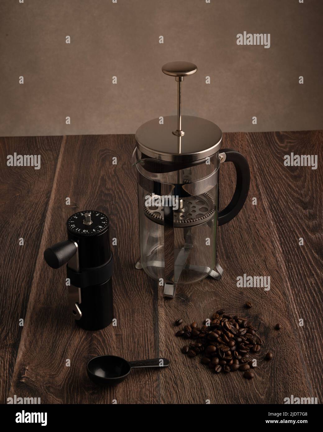Eine Kaffeepresse, Kaffeemühle, Kaffeesühle und Kaffeebohnen auf einer Tischplatte aus dunklem Holz mit Platz für Kopien oben Stockfoto