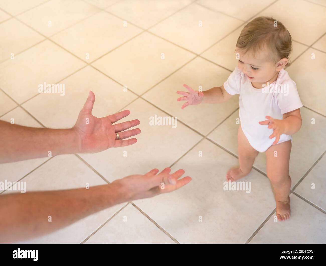 Der Vater greift das kleine Mädchen (6-11 Monate) an und macht erste Schritte Stockfoto