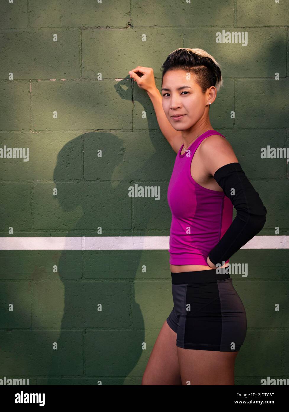 Porträt einer Sportlerin mit amputierter Hand, die gegen die Wand lehnt Stockfoto