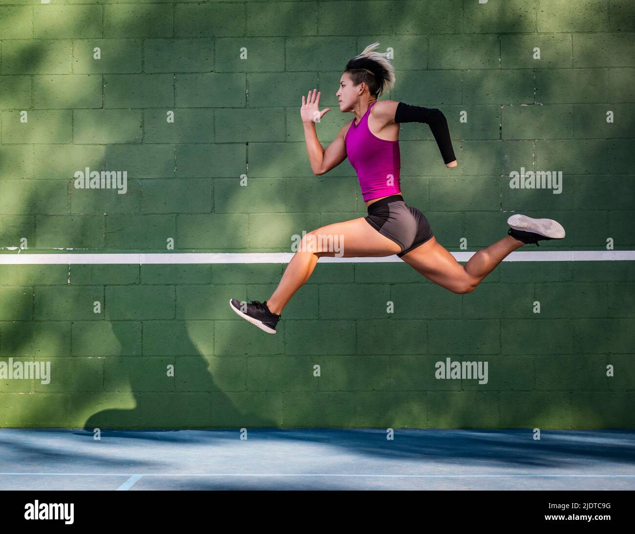 Sportlerin mit Armprothese, die gegen die Wand läuft Stockfoto
