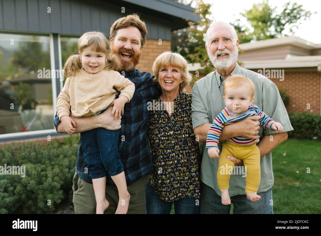 Porträt einer lächelnden dreigenerierten Familie mit Kindern (2-3, 4-5) im Hinterhof Stockfoto