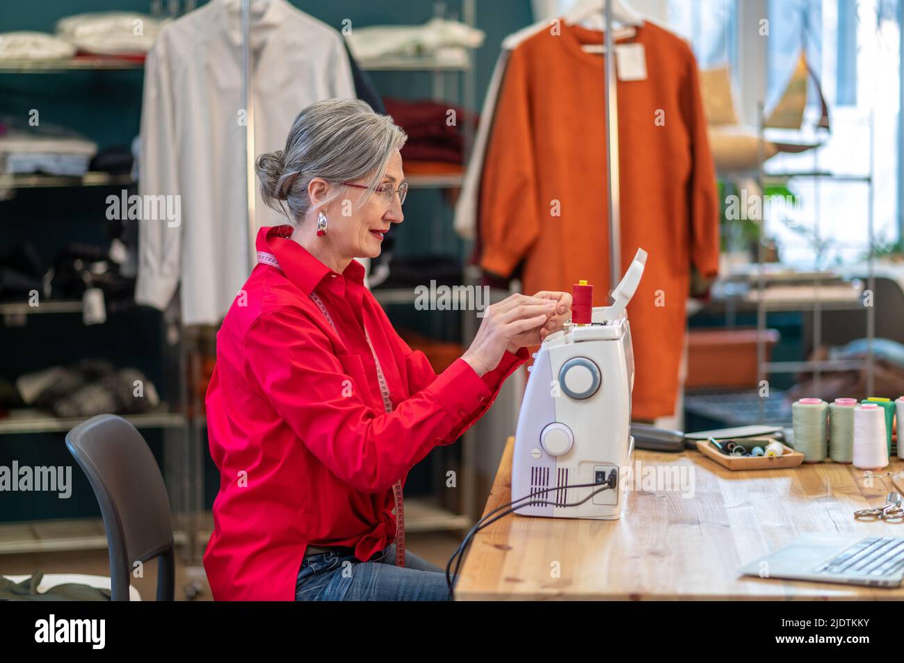 Frau, die seitlich zur Kamera auf der Nähmaschine sitzt Stockfoto