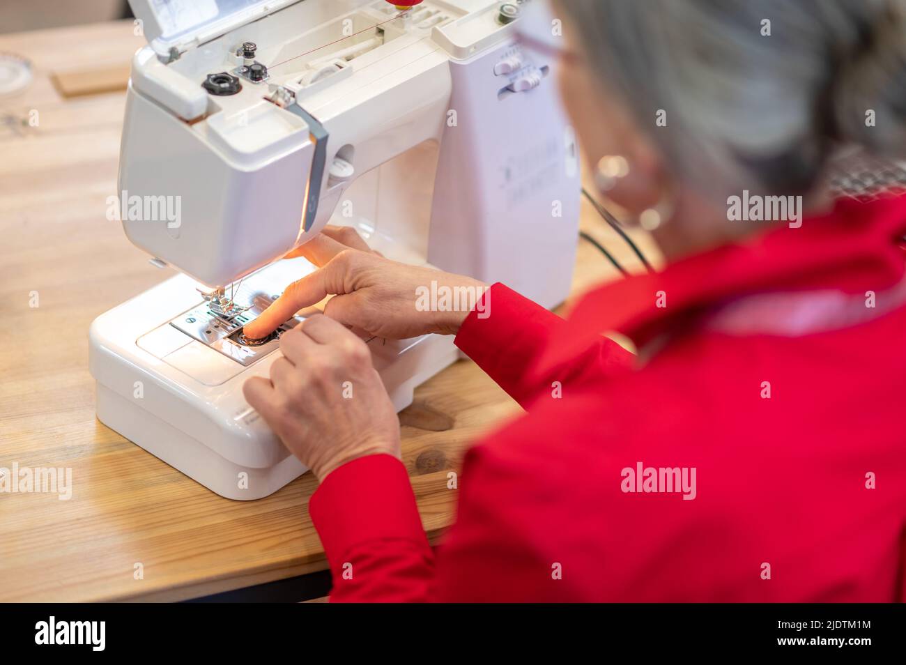 Rückansicht einer Frau, die eine Nähmaschine aufsetzt Stockfoto