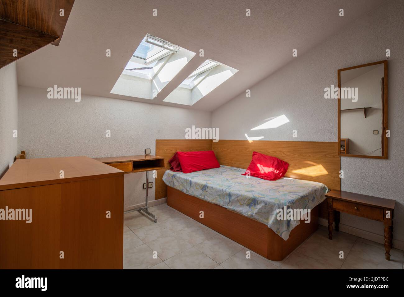 Kleines Schlafzimmer mit Einzelbett, Schreibtisch und Dachfenster in der Dachschräge Stockfoto