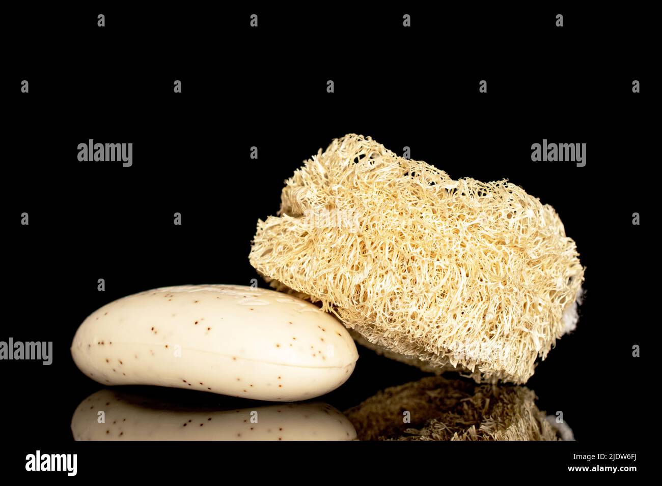 Ein Lufah-Duschschwamm und ein Stück Seife, Nahaufnahme, isoliert auf schwarzem Hintergrund. Stockfoto