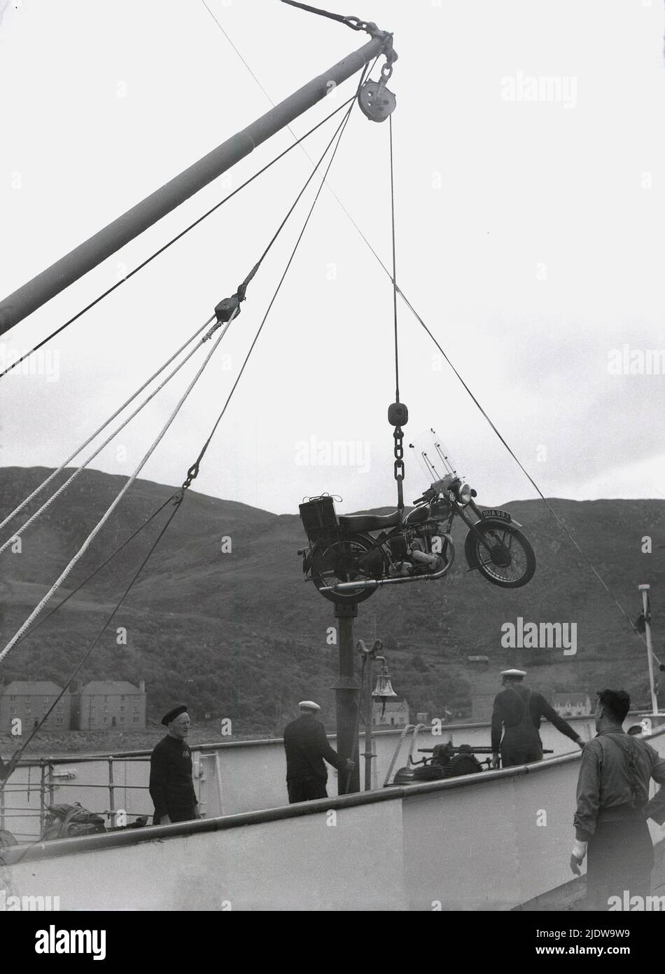 1950s, historisch, am Hafen von Mallaig in den schottischen Highlands, Schottland, Großbritannien, wurde ein Motorrad der damaligen Zeit auf einer Riemenscheibe auf ein Schiff geladen. Das Motorrad ist ein Ariel 'Square Four', auch bekannt als der 'Squariel'. Hergestellt vom Briitsh-Hersteller Ariel Motors Ltd. Aus Birmingham aus dem Jahr 1953, hatte es einen 1000cc 4-Zylinder-Motor - den größten jemals in Großbritannien produzierten - was es ideal für Motorradtouren machte. Stockfoto