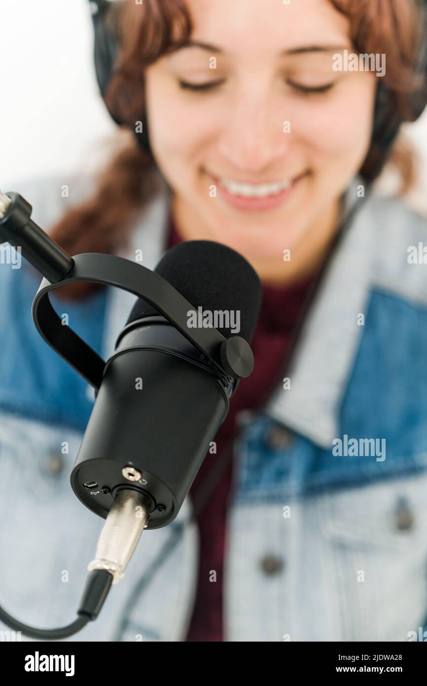 Nahaufnahme einer lächelnden Frau mit Mikrofon vor dem Gesicht Stockfoto
