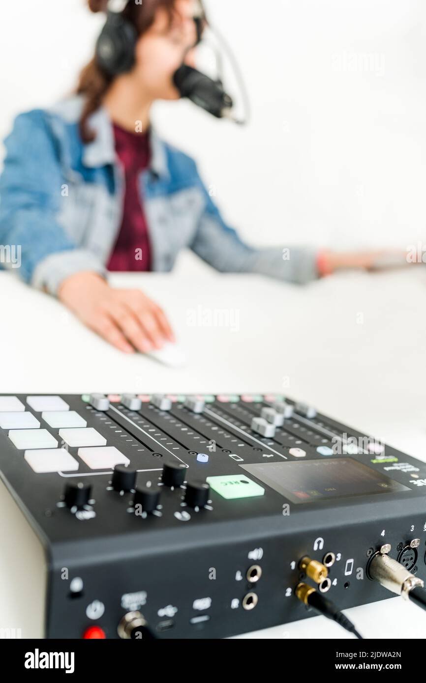 Sound Mischpult mit weiblichem Sprechen ins Mikrofon im Hintergrund Stockfoto