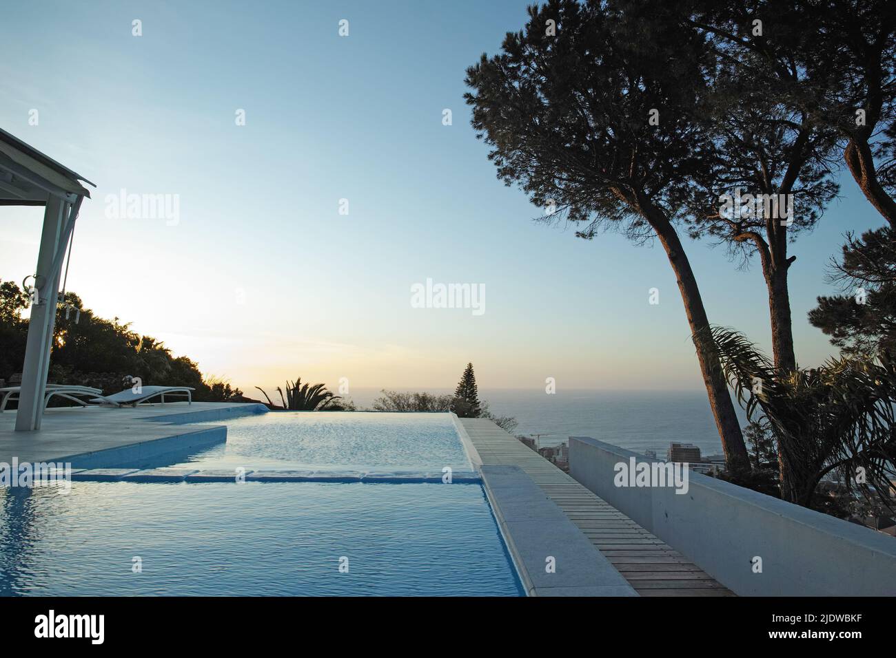 Malerischer Blick auf den Sonnenuntergang auf einen unendlichen Swimmingpool mit einem Ozean im Hintergrund. Luxuriöser Außenpool auf einer Terrasse, Terrasse, Dach einer Wohnung, Haus, Hotel Stockfoto
