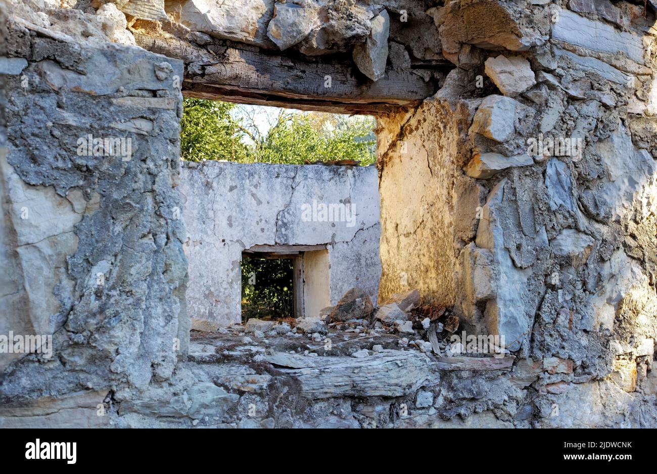 Verlassene alte kaputte Haus mit dicken zerbröckelnden Steinmauern. Ruinen eines beschädigten ländlichen Hauses mit einem leeren Fensterrahmen. Verwittertes antikes Bauernhaus mit Stockfoto