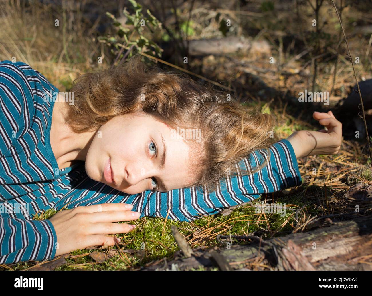 Schöne Teenager-Mädchen liegt auf dem grünen Moos im Wald genießen das Sonnenlicht. Entspannung im Freien, die Lebenskraft der Erde. hallo Frühling, so Stockfoto