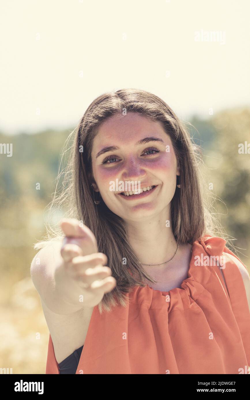 Porträt einer glücklichen jungen Frau, die sich auf die Hand ihres Freundes oder Partners streckt, während sie in einem ländlichen Gebiet vorbei geht. Pärchen genießen eine Wanderung in der Natur. Hochwertige Fotos Stockfoto