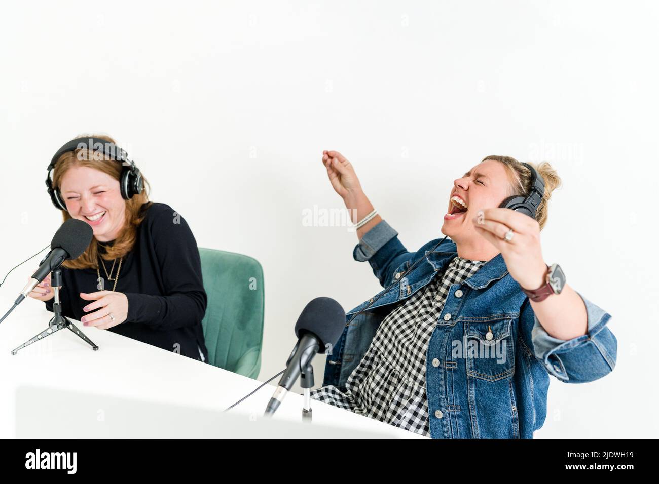 Zwei Frauen, die mit Kopfhörern vor Mikrofonen Aufnahmen Stockfoto