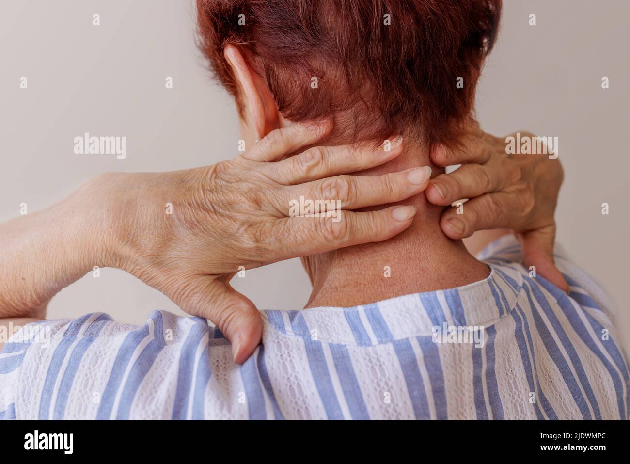 Hautnah massieren die Hände einer älteren Frau ihren eigenen Hals Neurologische Erkrankungen Stockfoto