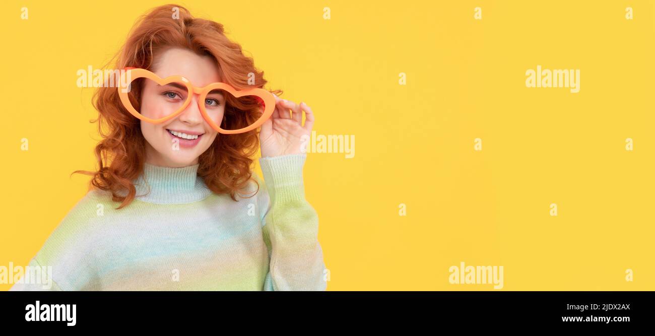 Glücklich Rotschopf Frau tragen lustige Party-Brille auf gelbem Hintergrund, Feier. Frau isoliert Gesicht Porträt, Banner mit Kopieplatz. Stockfoto