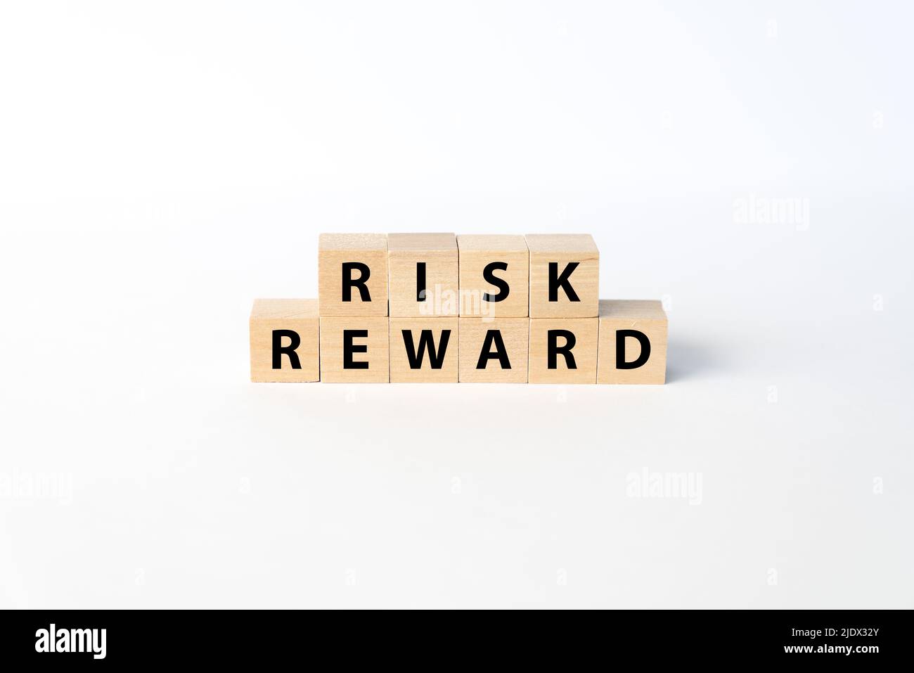 Die Konzepte von Risiko und Rendite wurden mit Holzblöcken auf weißem Hintergrund geschrieben Stockfoto