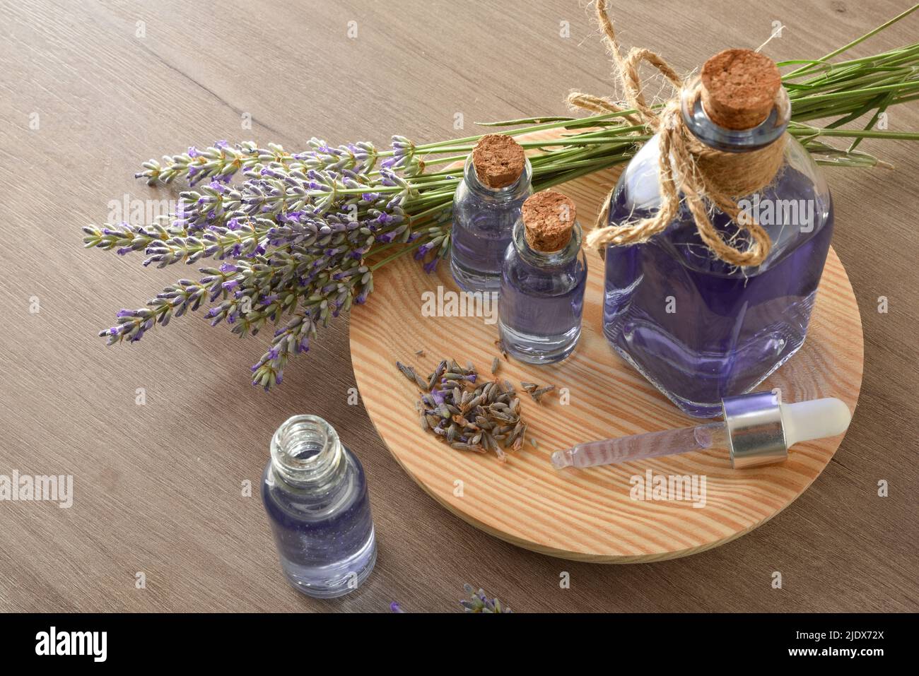 Glasbehälter mit Lavendelextrakt mit Blumensträußen von Spikes um auf Holz in einem Raum. Draufsicht. Horizontale Zusammensetzung. Stockfoto