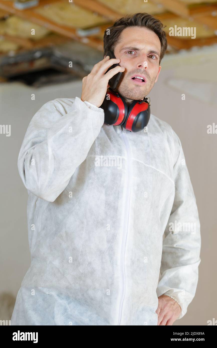 Mann, der mit einem Mobiltelefon in Schutzkleidung arbeitet Stockfoto