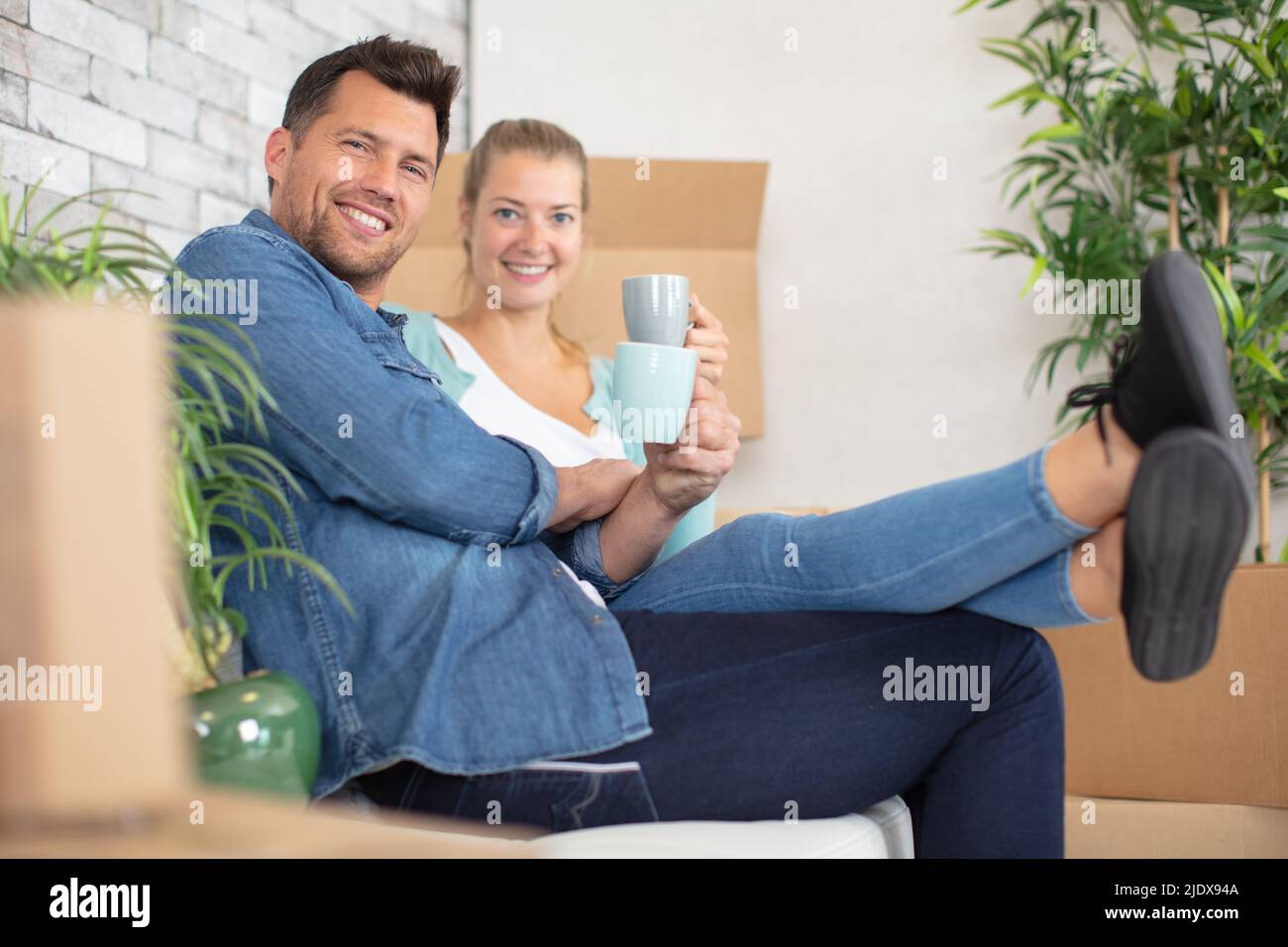 Paar entspannen sich auf dem Sofa mit einem heißen Getränk in neuem Zuhause Stockfoto