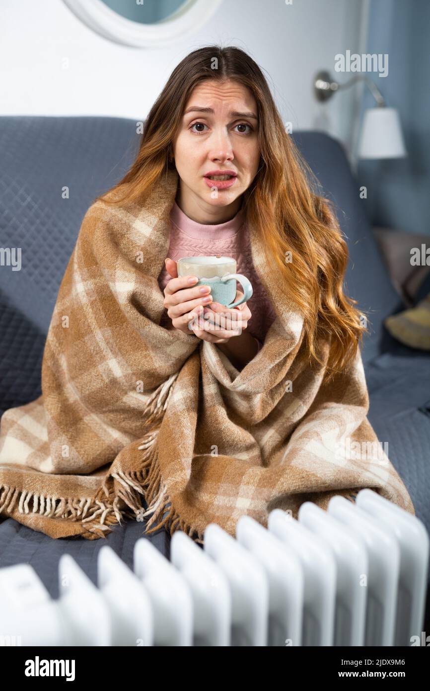 Junge Frau versucht, sich zu Hause zu wärmen Stockfoto