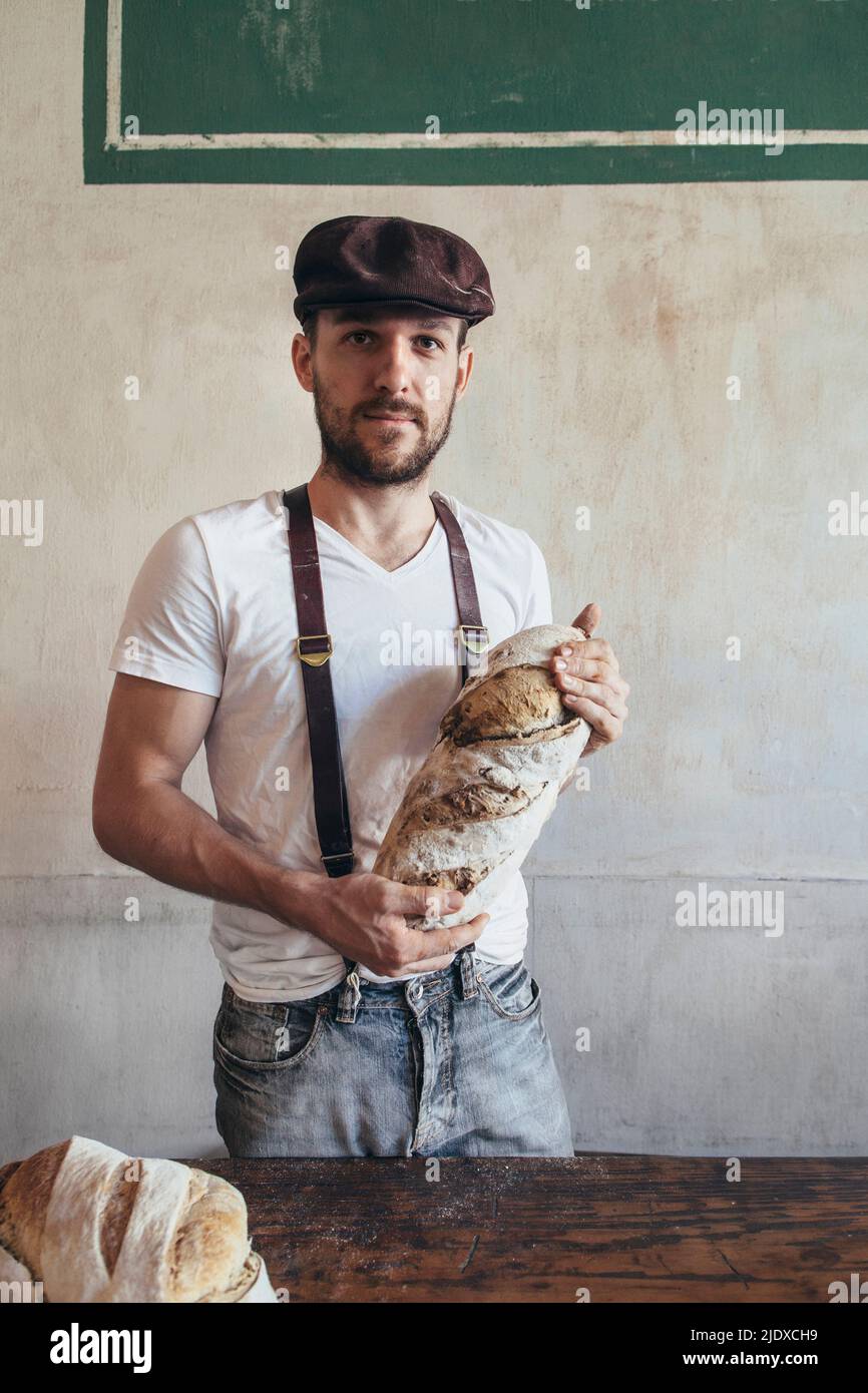 Junger Bäcker mit frisch gebackenem Landbrot in der Bäckerei Stockfoto