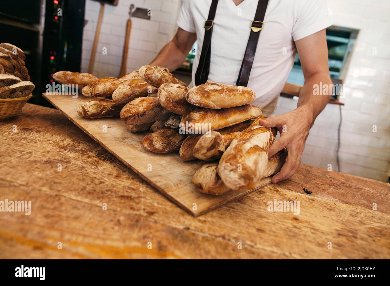 Baker hält Tablett mit frischen Baguettes in der Bäckerei Stockfoto