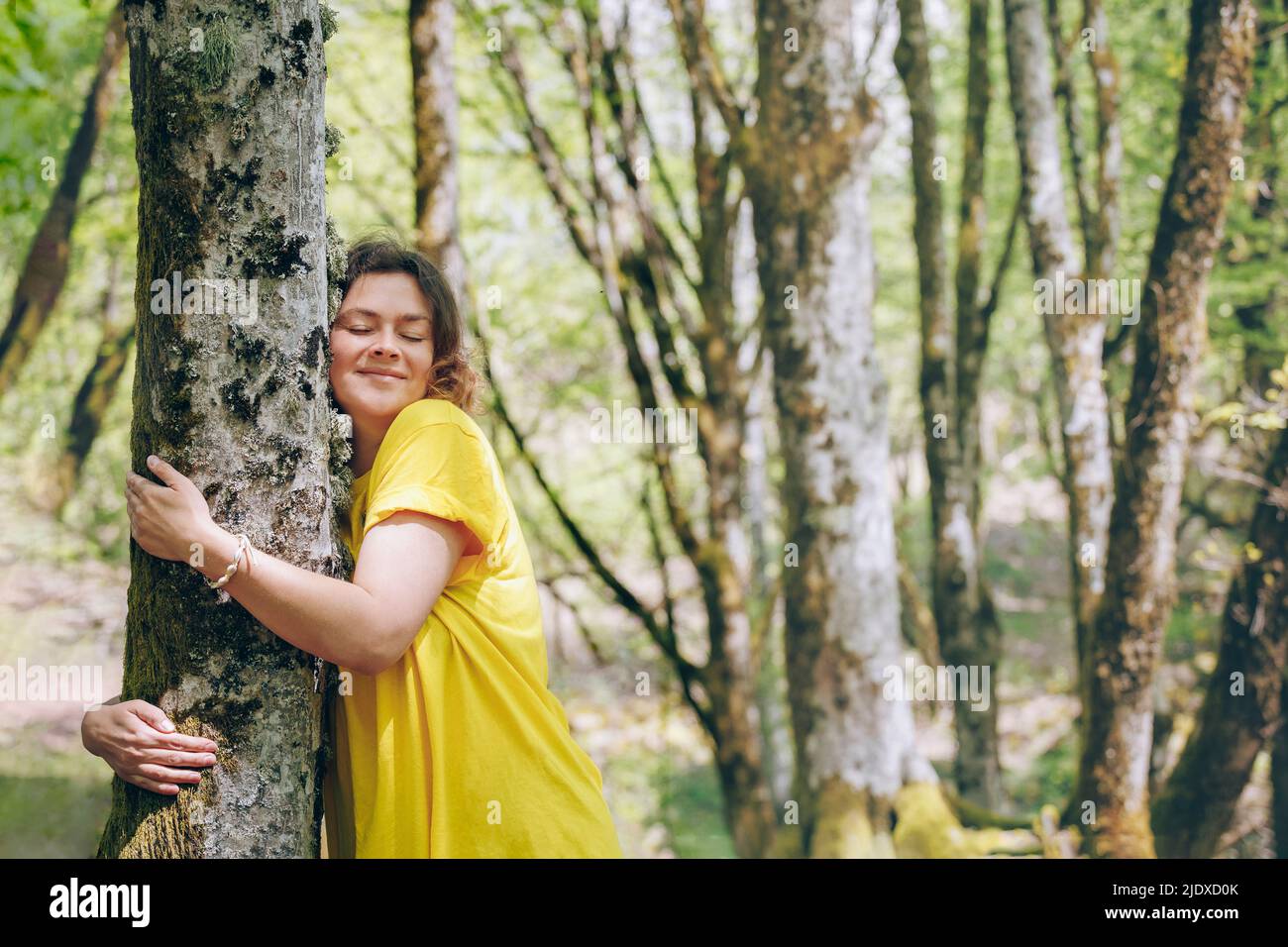 Frau umarmt Baum im Wald im Urlaub Stockfoto