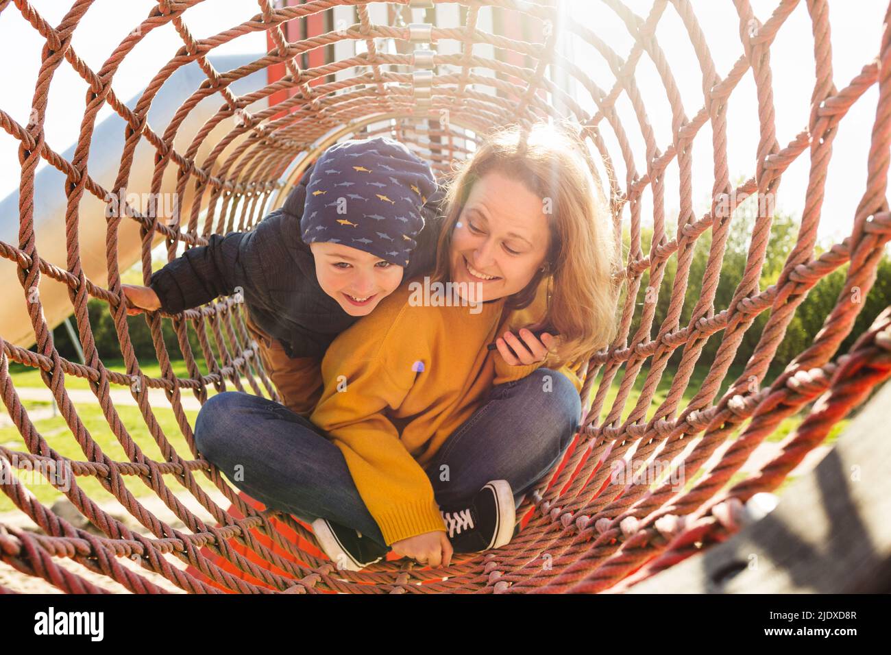 Glückliche Mutter mit Sohn, der in der Dschungelhalle auf dem Spielplatz spielt Stockfoto