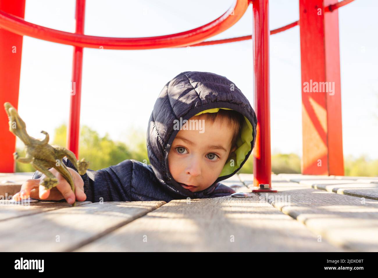 Netter Junge mit Dinosaurier-Spielzeug, das auf dem Spielplatz spielt Stockfoto