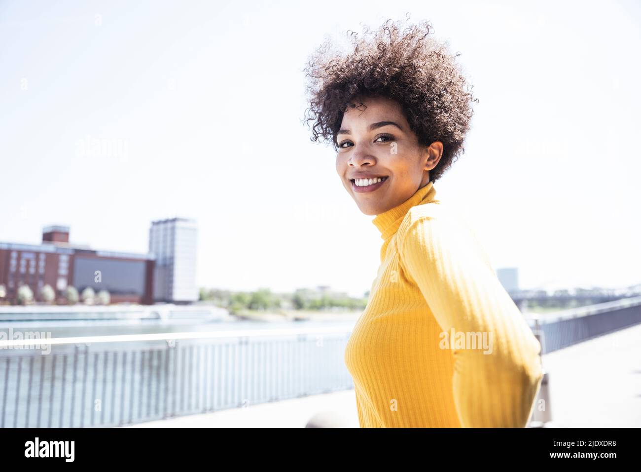 Glückliche Frau mit Afro-Frisur an der Promenade an sonnigen Tag Stockfoto