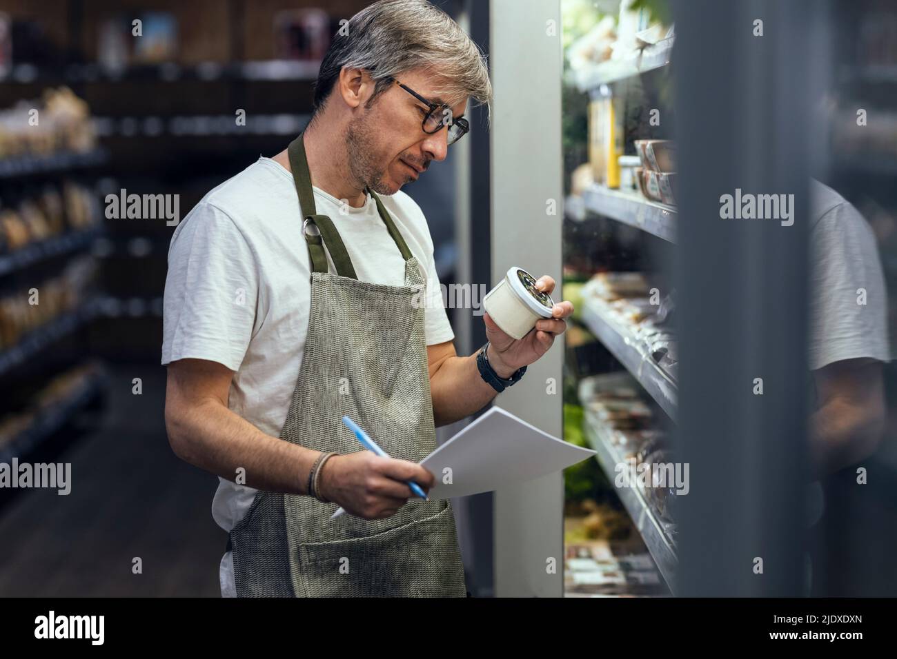 Ladenbesitzer, der Container untersucht, die im Bio-Markt arbeiten Stockfoto