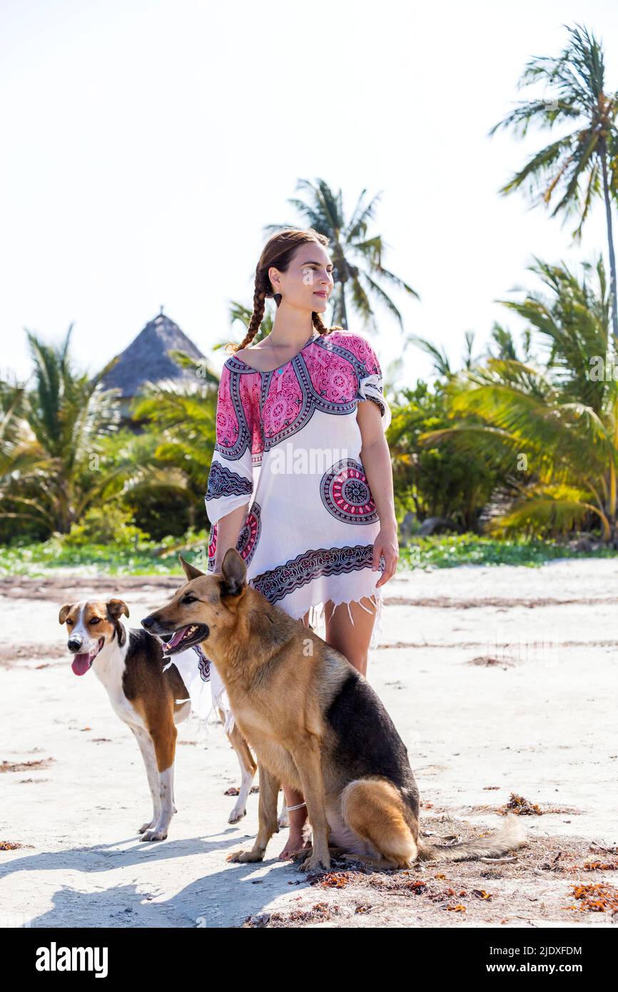 Nachdenkliche Frau mit Hunden am Strand im Urlaub Stockfoto
