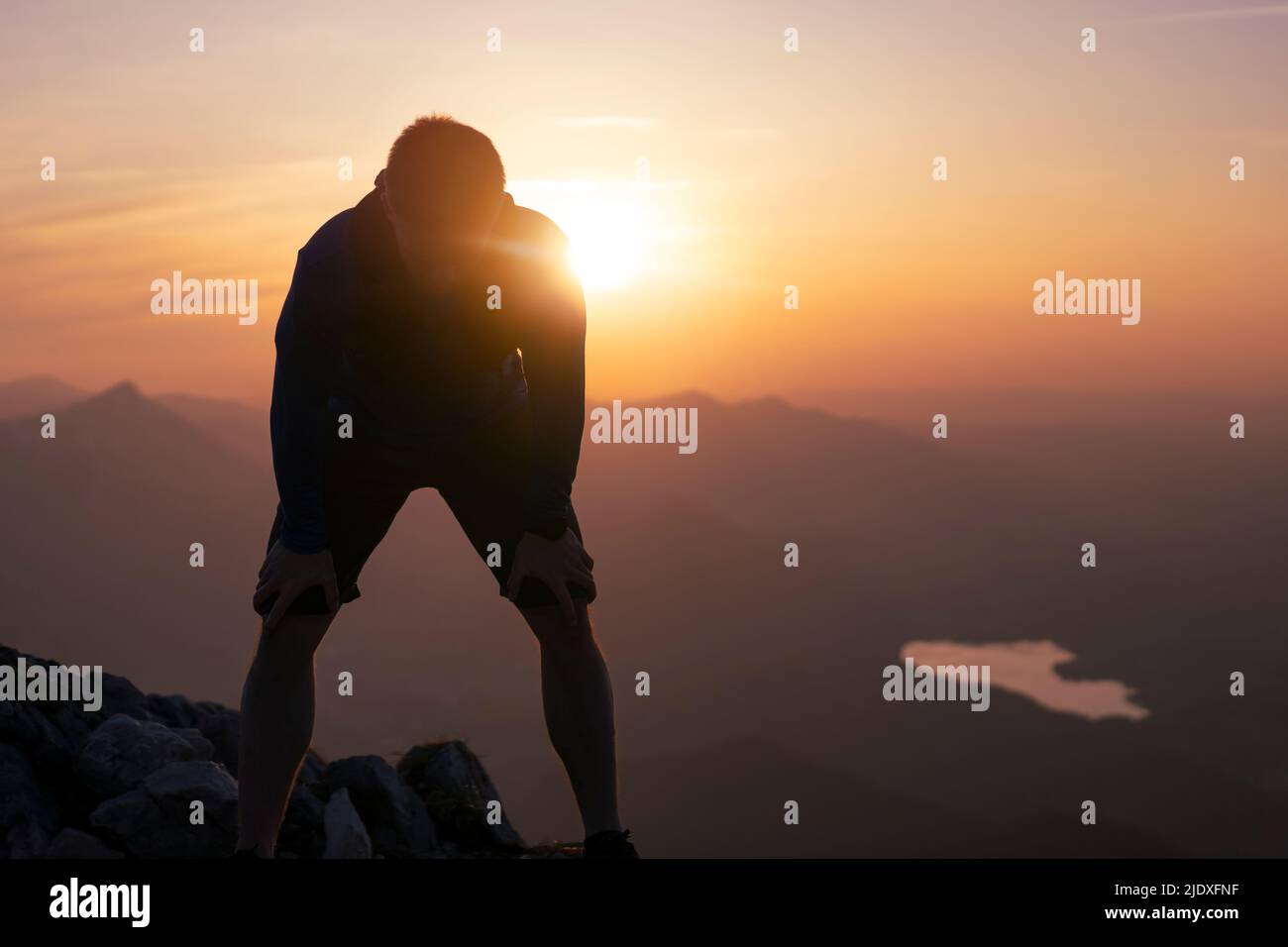 Müde Wanderer mit Händen auf den Knien am Berg Stockfoto
