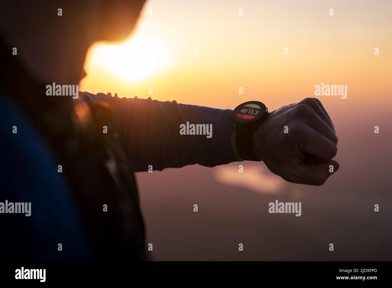 Mann schaut bei Sonnenuntergang auf die Smartwatch Stockfoto