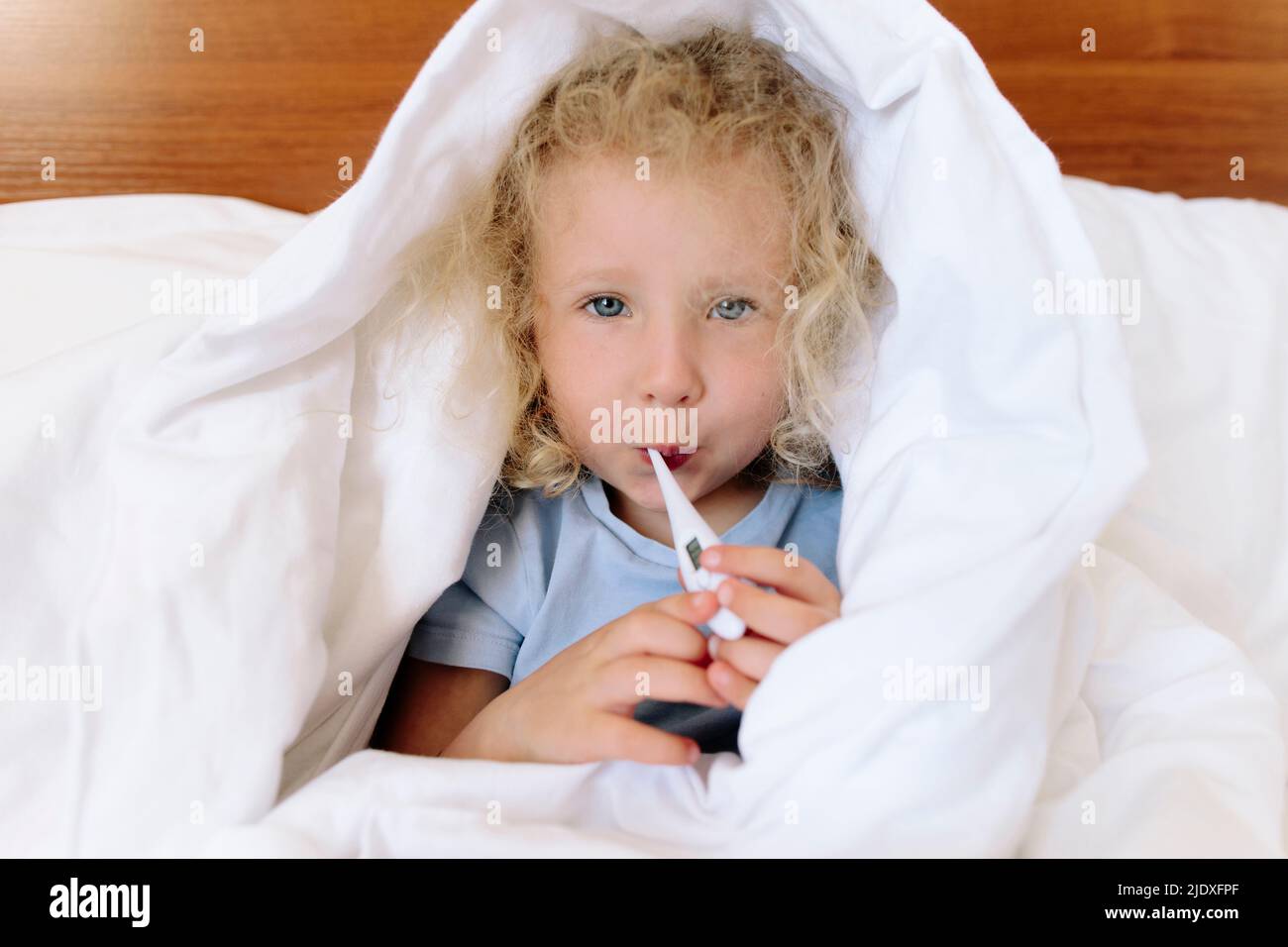 Kranke Mädchen in Decke mit Digitalthermometer gewickelt zu Hause Stockfoto