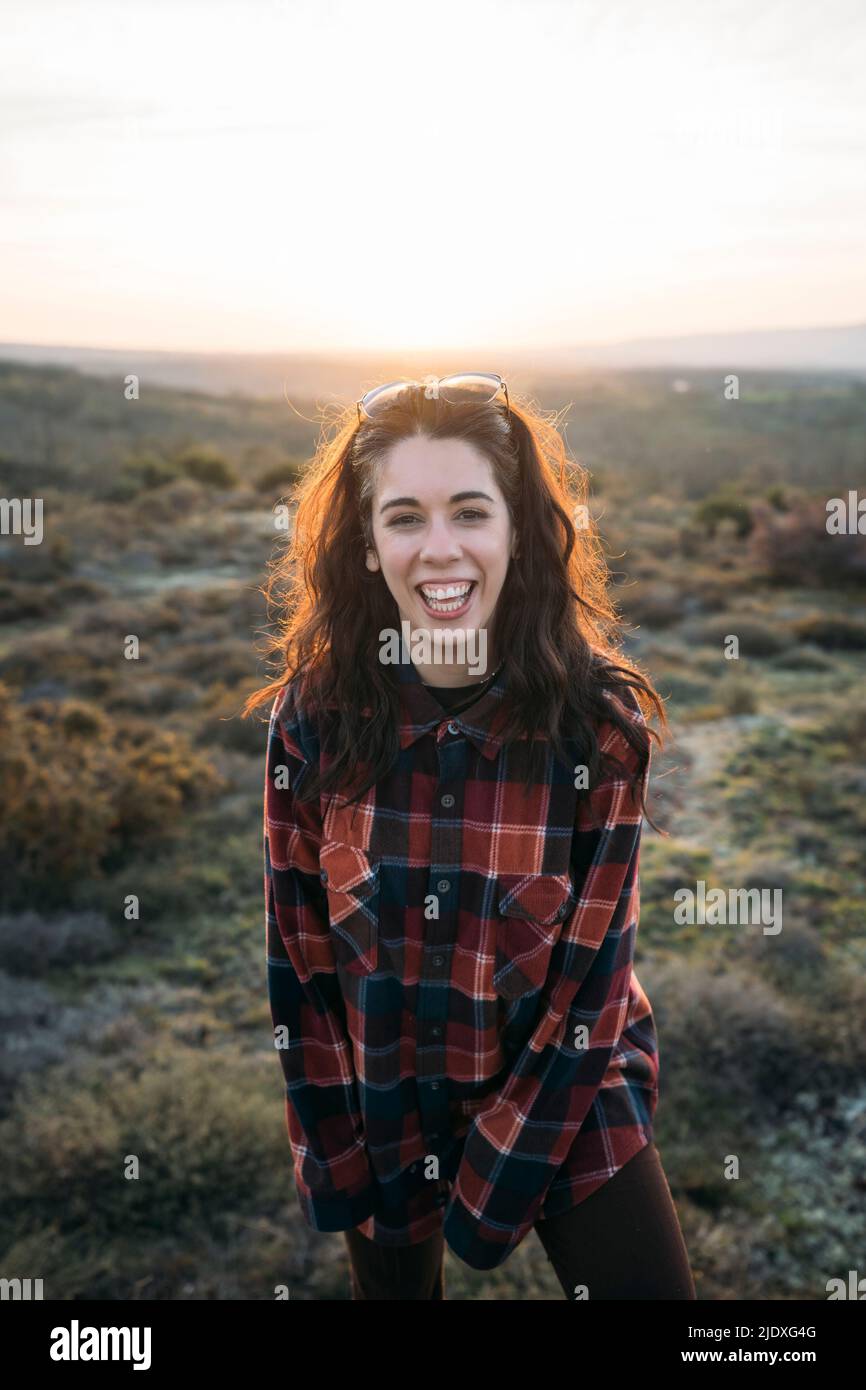 Fröhliche Frau im karierten Hemd bei Sonnenuntergang Stockfoto