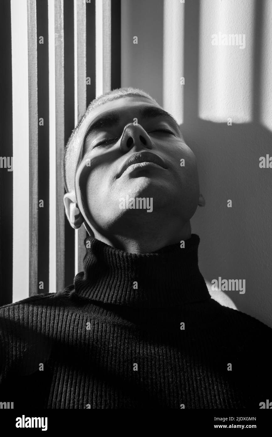 Junger Mann mit Rollkragen an der Wand gelehnt Stockfoto