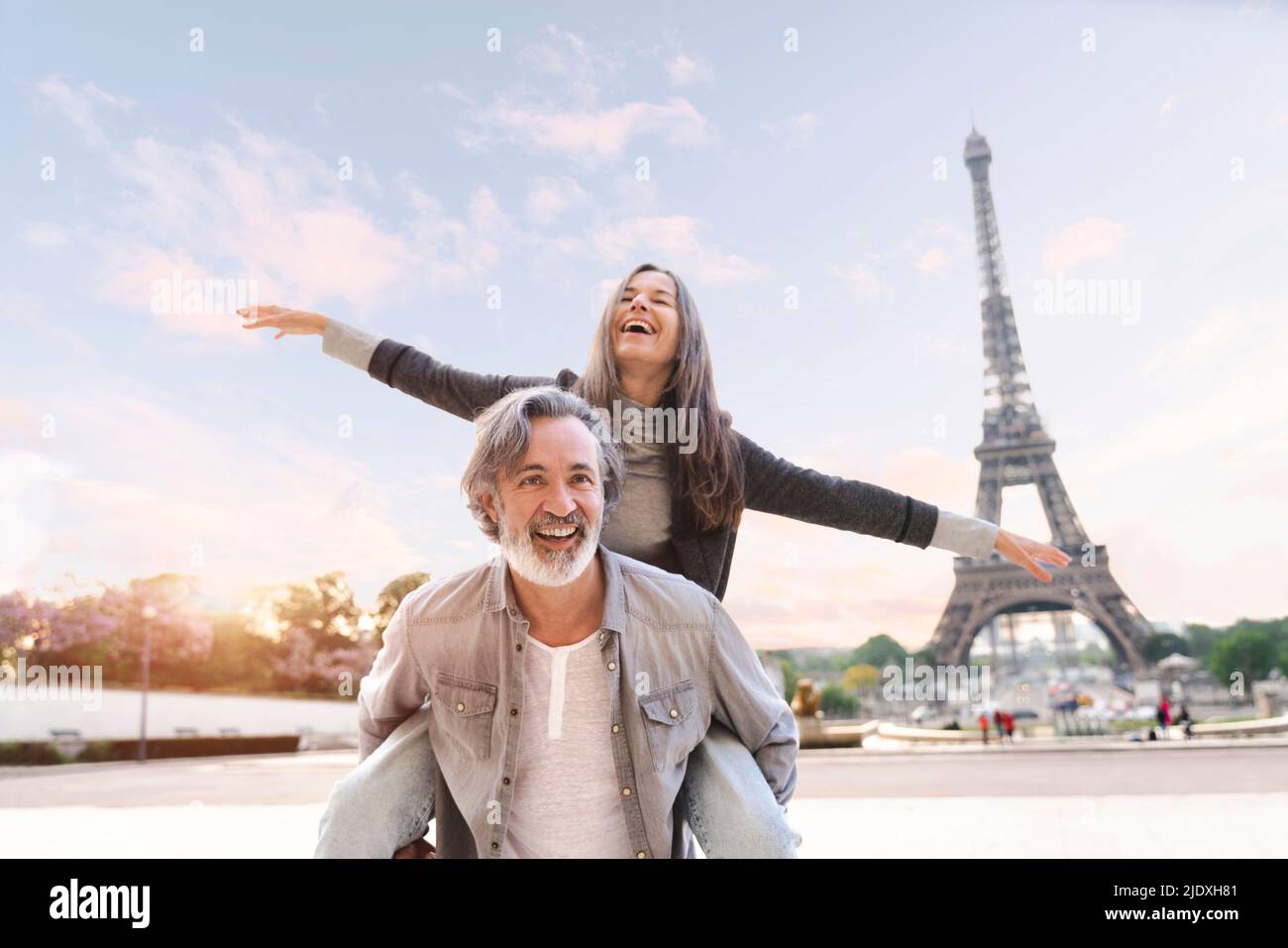 Glücklicher reifer Mann, der der Frau vor dem Eiffelturm, Paris, Frankreich, eine Huckepack-Fahrt gab Stockfoto