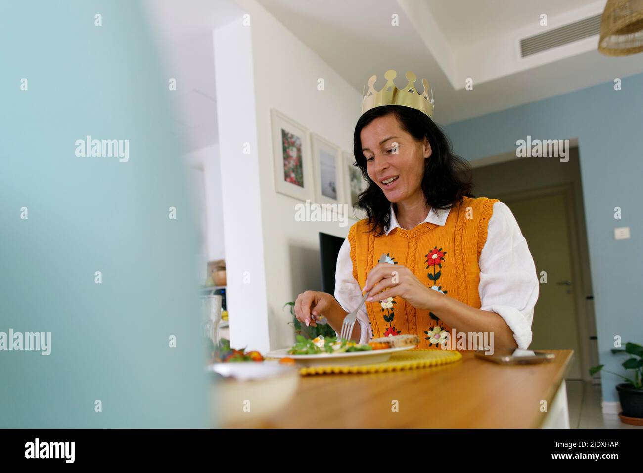 Frau trägt Krone essen zu Hause Stockfoto