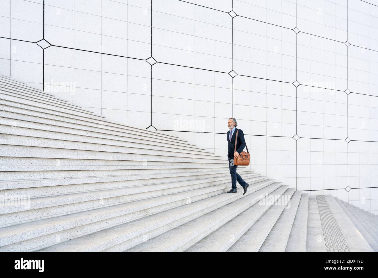 Reifer Geschäftsmann mit Tasche, die sich auf Stufen hochbewegt Stockfoto