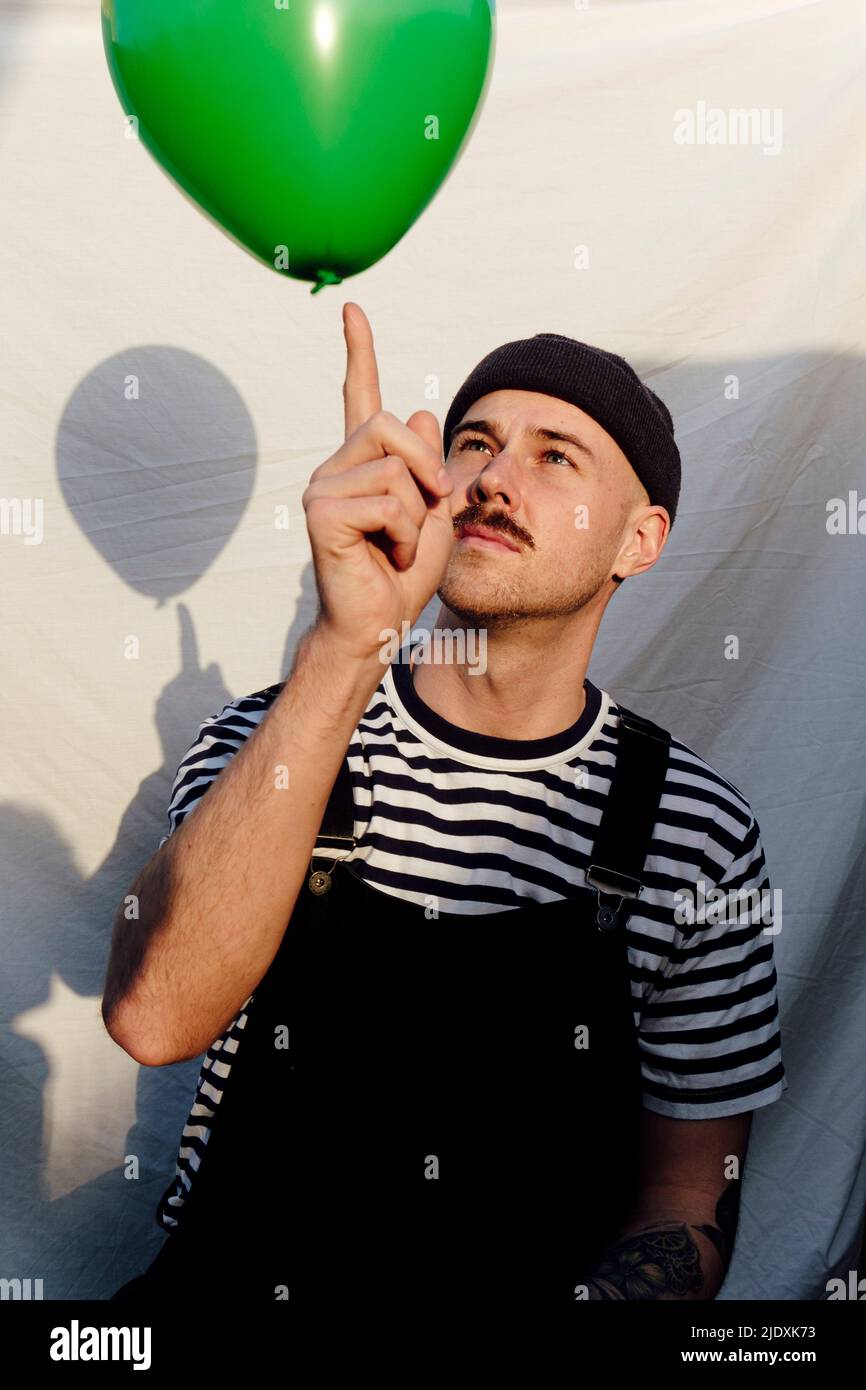 Mann spielt mit grünem Ballon vor weißem Hintergrund Stockfoto