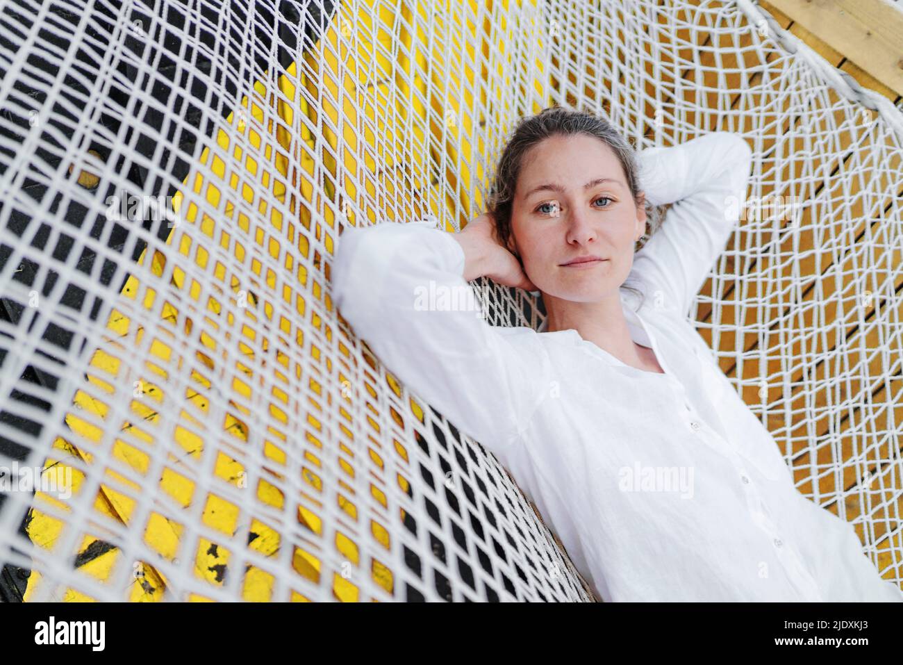 Schöne Frau, die mit den Händen hinter dem Kopf auf der Hängematte ruht Stockfoto