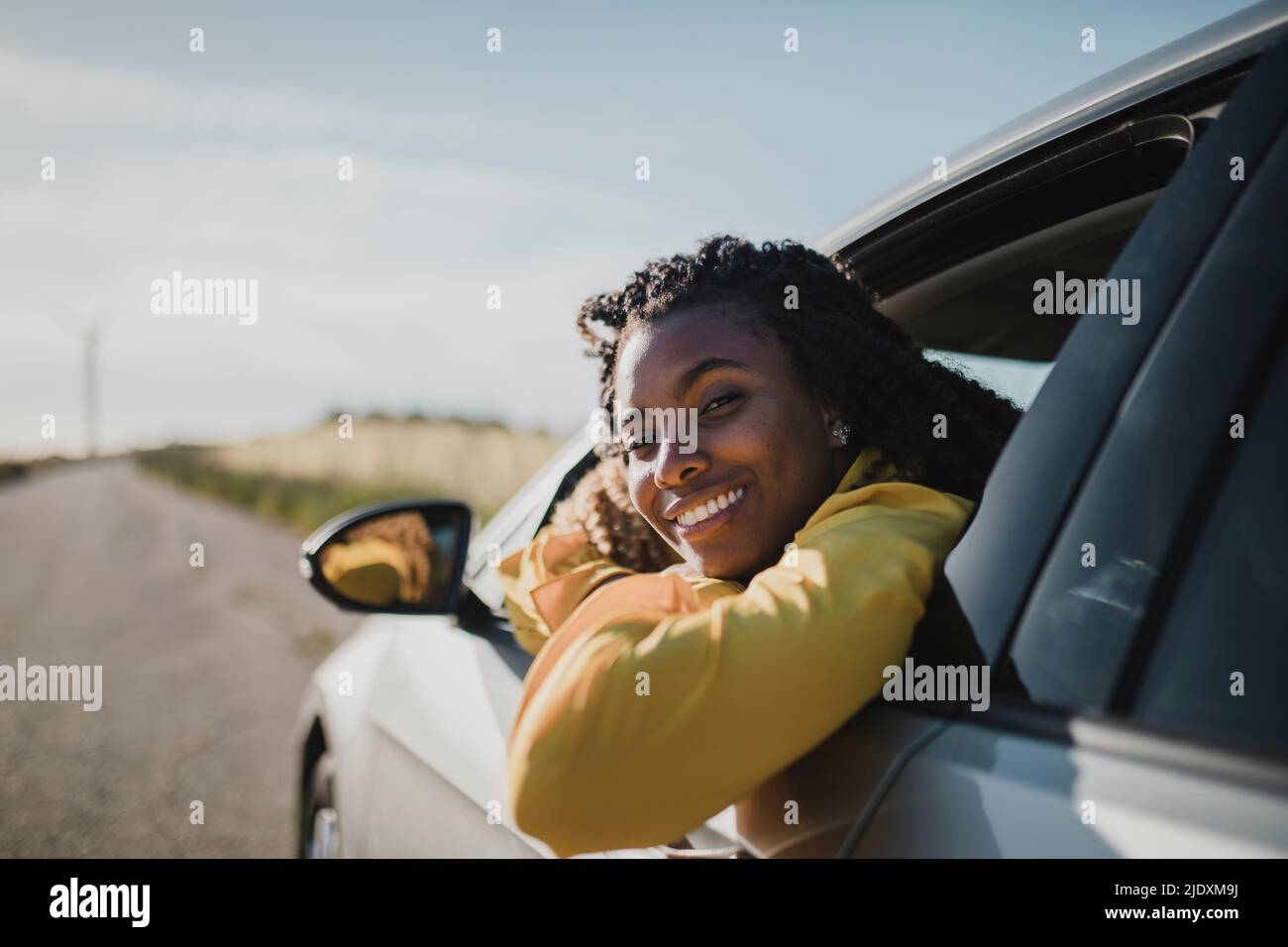 Lächelnde Frau, die durch das Autofenster schaut Stockfoto