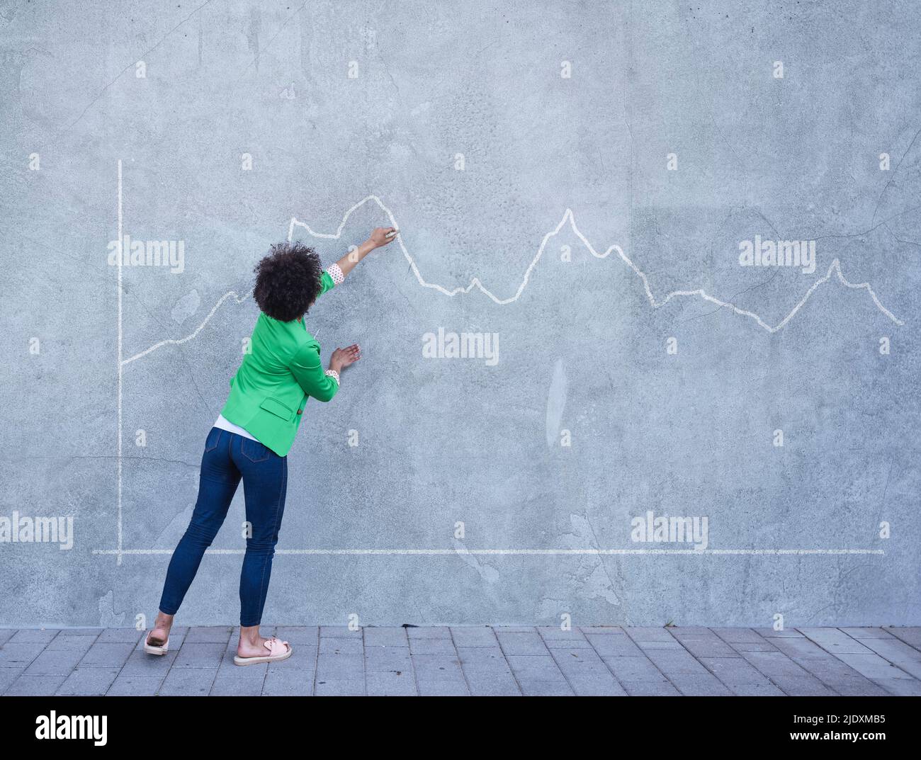 Junge Frau, die auf ein Diagramm zeigt, das auf die Wand gemalt ist Stockfoto