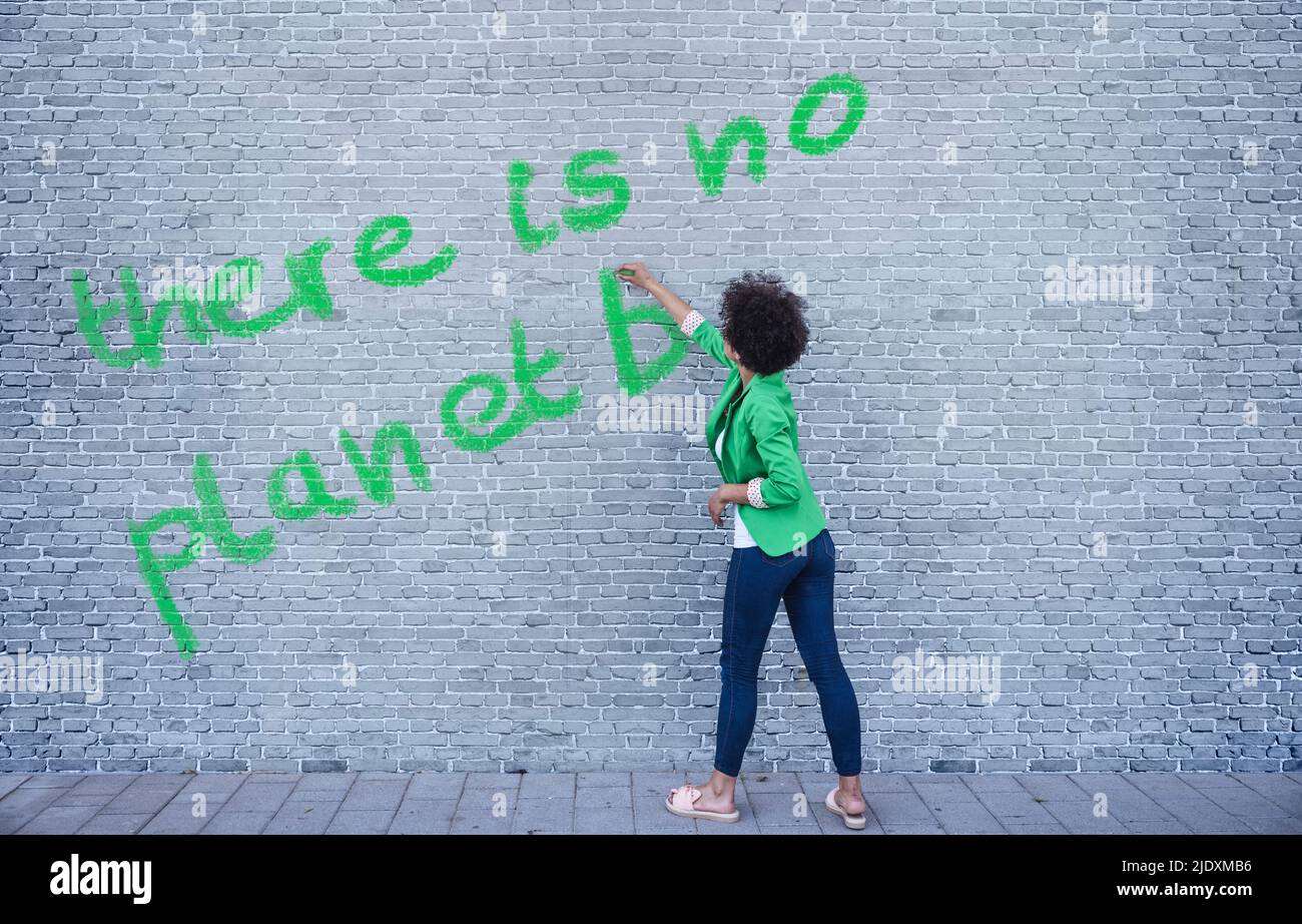 Junge Frau schreibt Es ist kein Planet B an der Wand Stockfoto