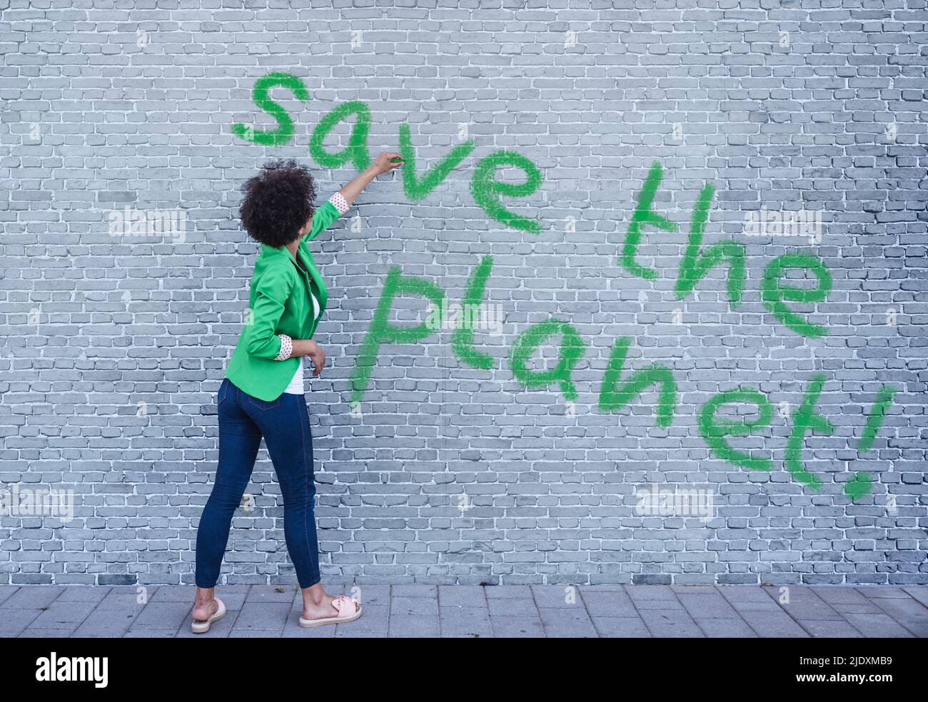 Junge Frau schreibt Save the Planet an der Wand Stockfoto